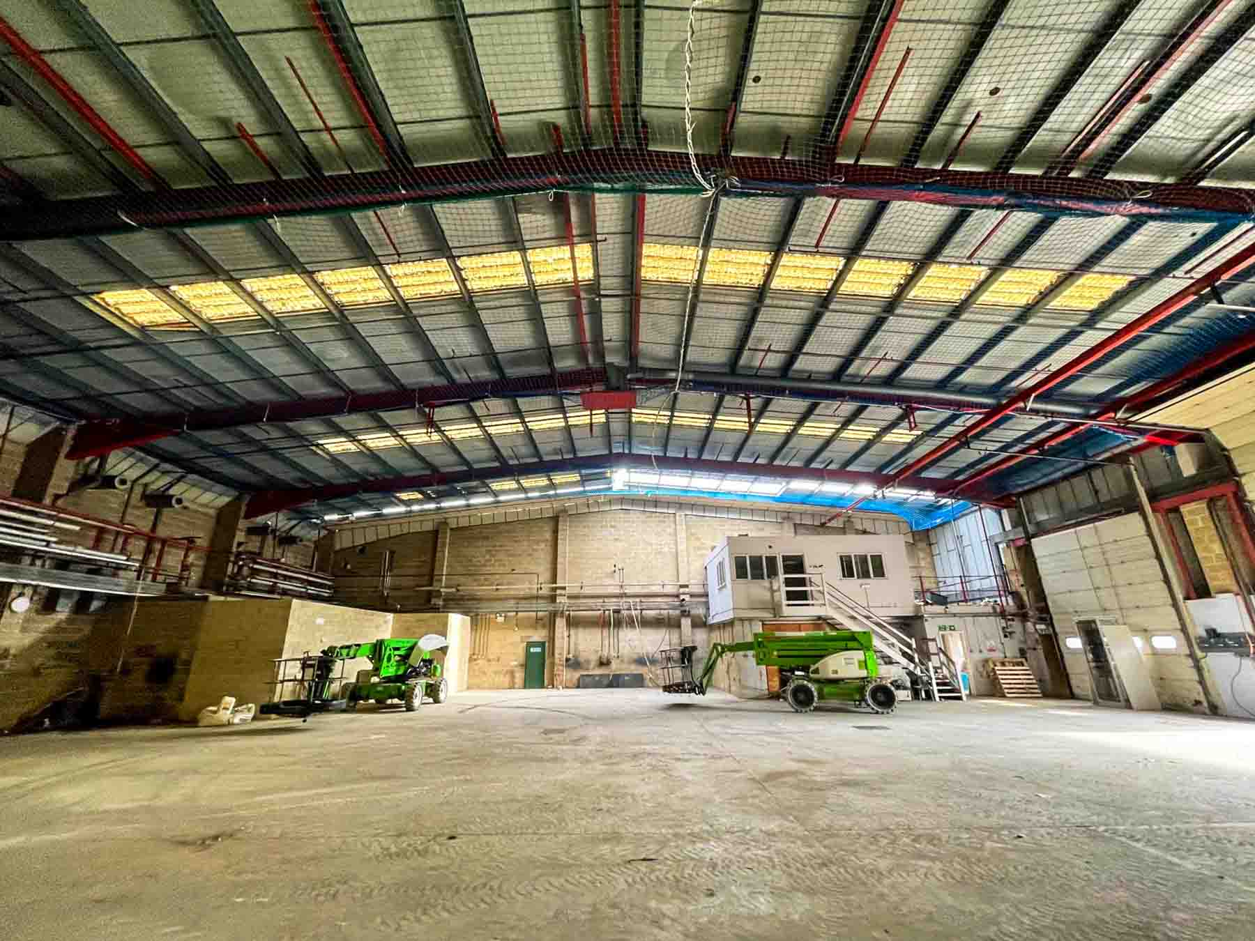 wide shot of inside of massive warehouse, looking up at roof during roof installation in elstree, hertfordshire